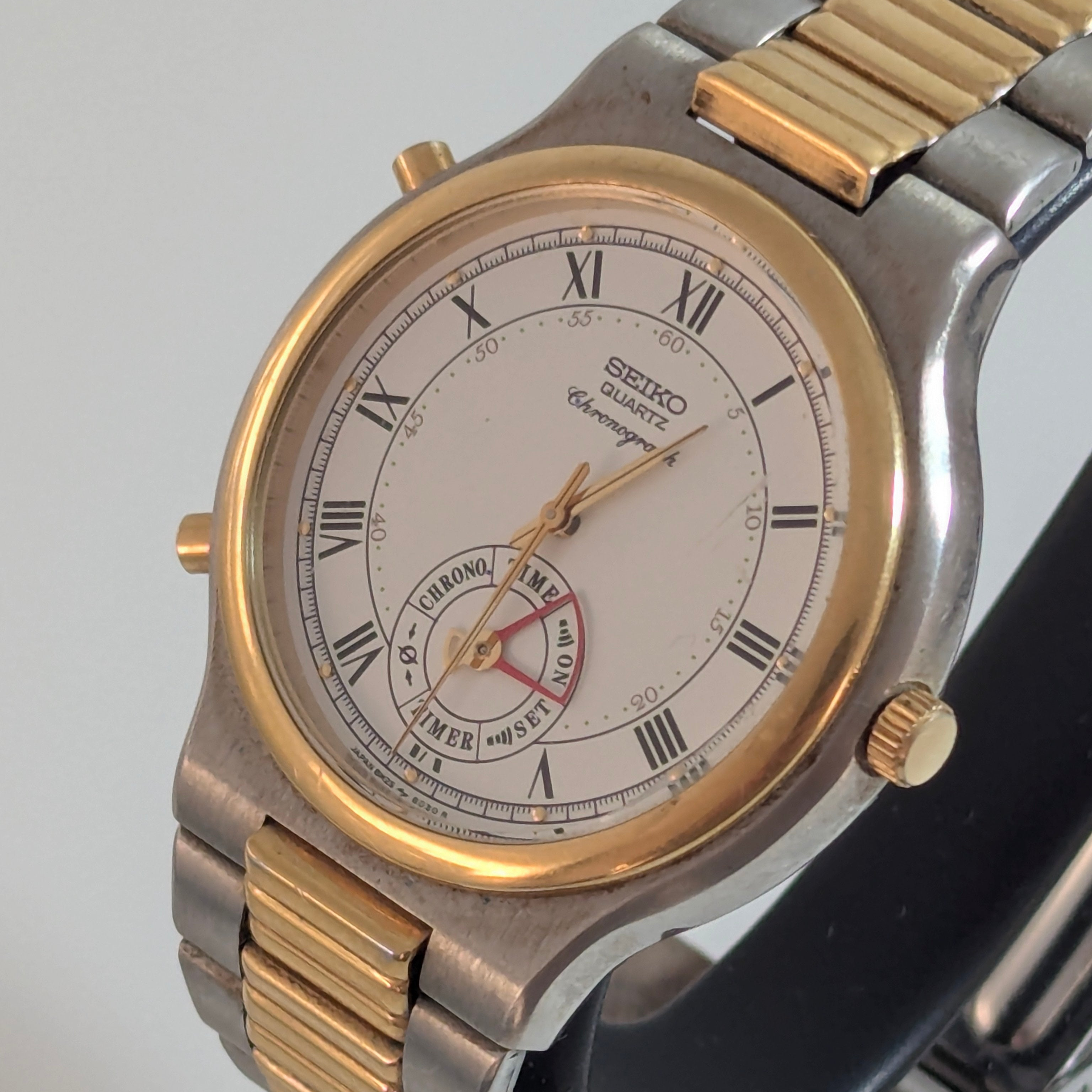 Vintage 1989 Seiko Dancing Hands alarm chronograph, 36mm two-tone case, white Roman numeral dial, mode indicator subdial, red alarm hand, ribbed two-tone bracelet, three-quarter view