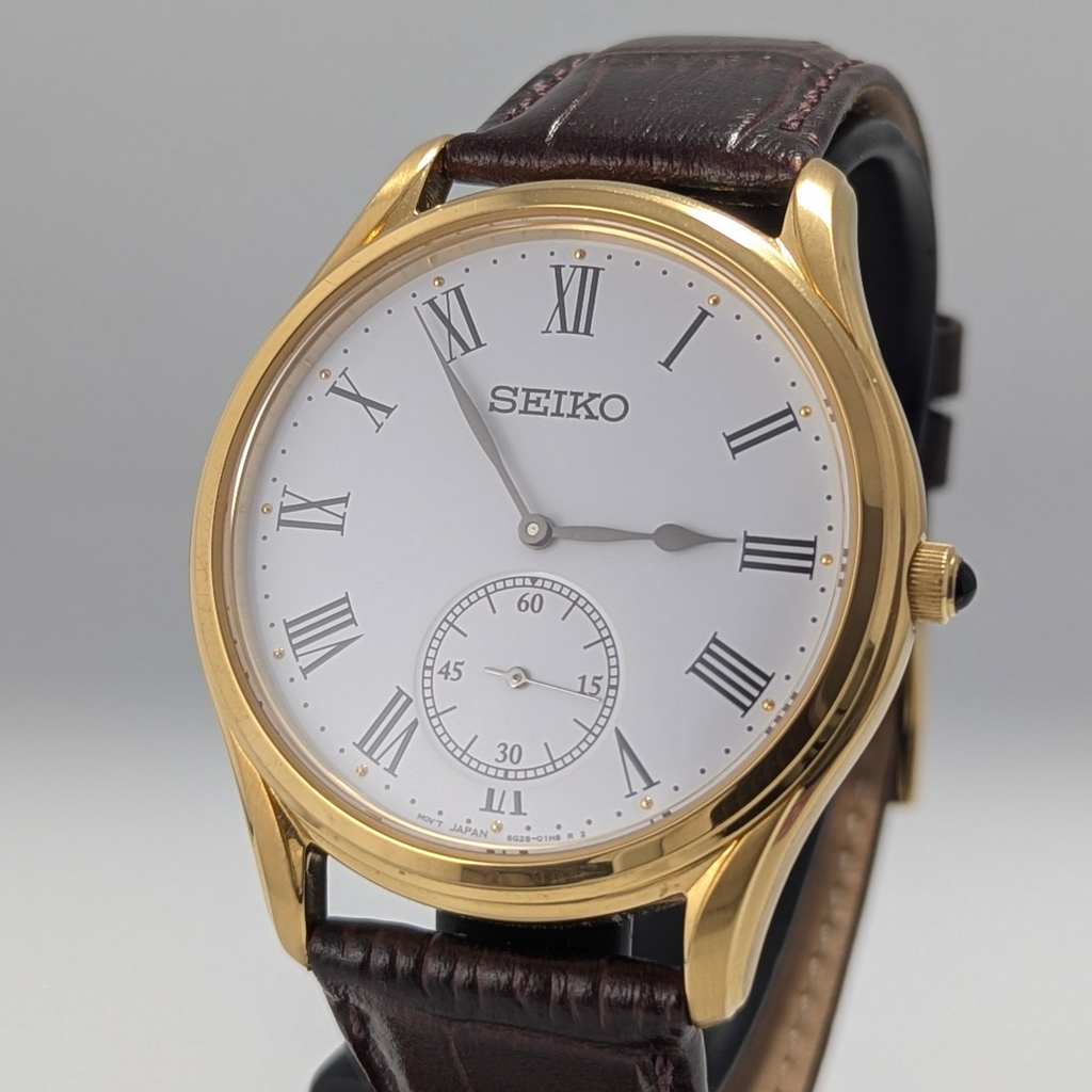 Seiko watch with gold case and brown leather strap on a gray background