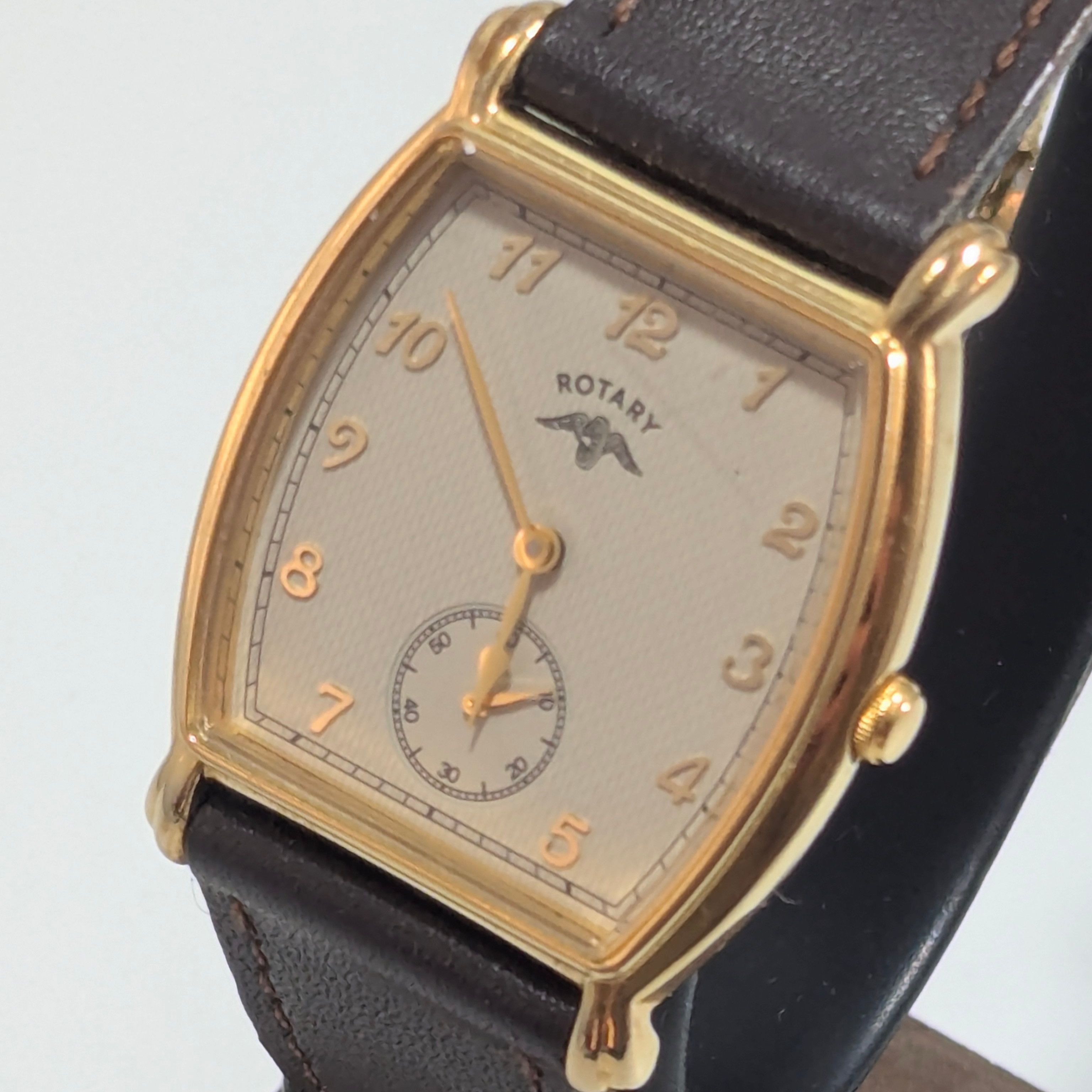 Vintage 1990s Rotary tonneau dress watch, gold-tone case, cream textured dial with Arabic numerals, subsidiary seconds, brown leather strap, three-quarter view
