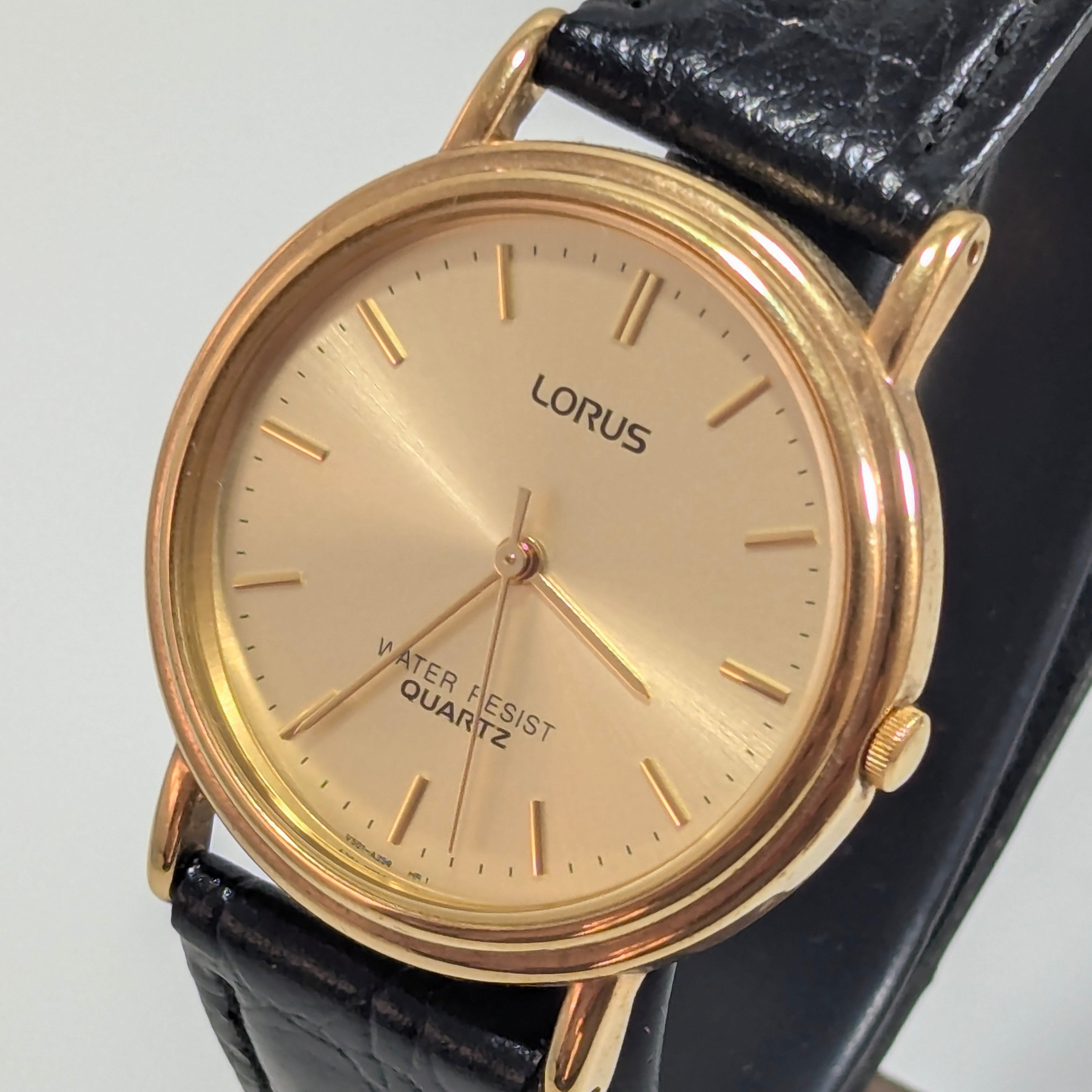 Lorus Classic quartz dress watch, 36mm gold-tone case with stepped bezel, champagne sunburst dial with gold baton indices, black croc-embossed leather strap, three-quarter view